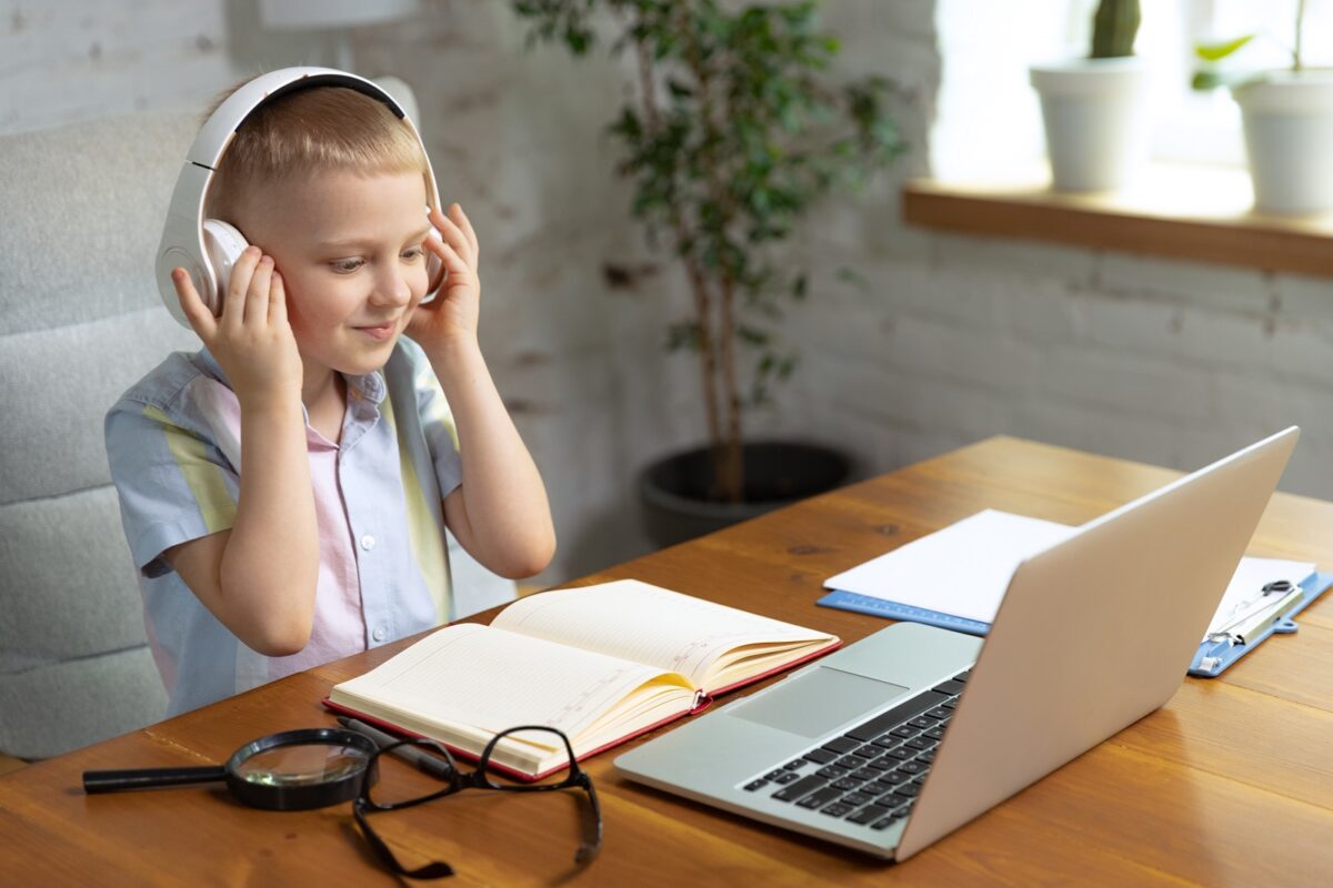 1600portrait little boy child headphones studying home looking laptop working with teacher online education